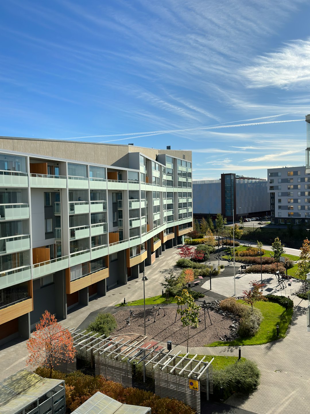Modern apartment buildings surround a green courtyard with a playground.