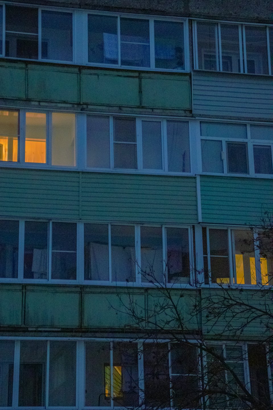 Green balconies on a residential building with illuminated windows.