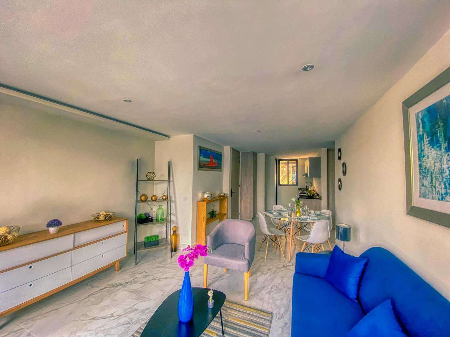 Modern living and dining room with blue sofa and orchids.