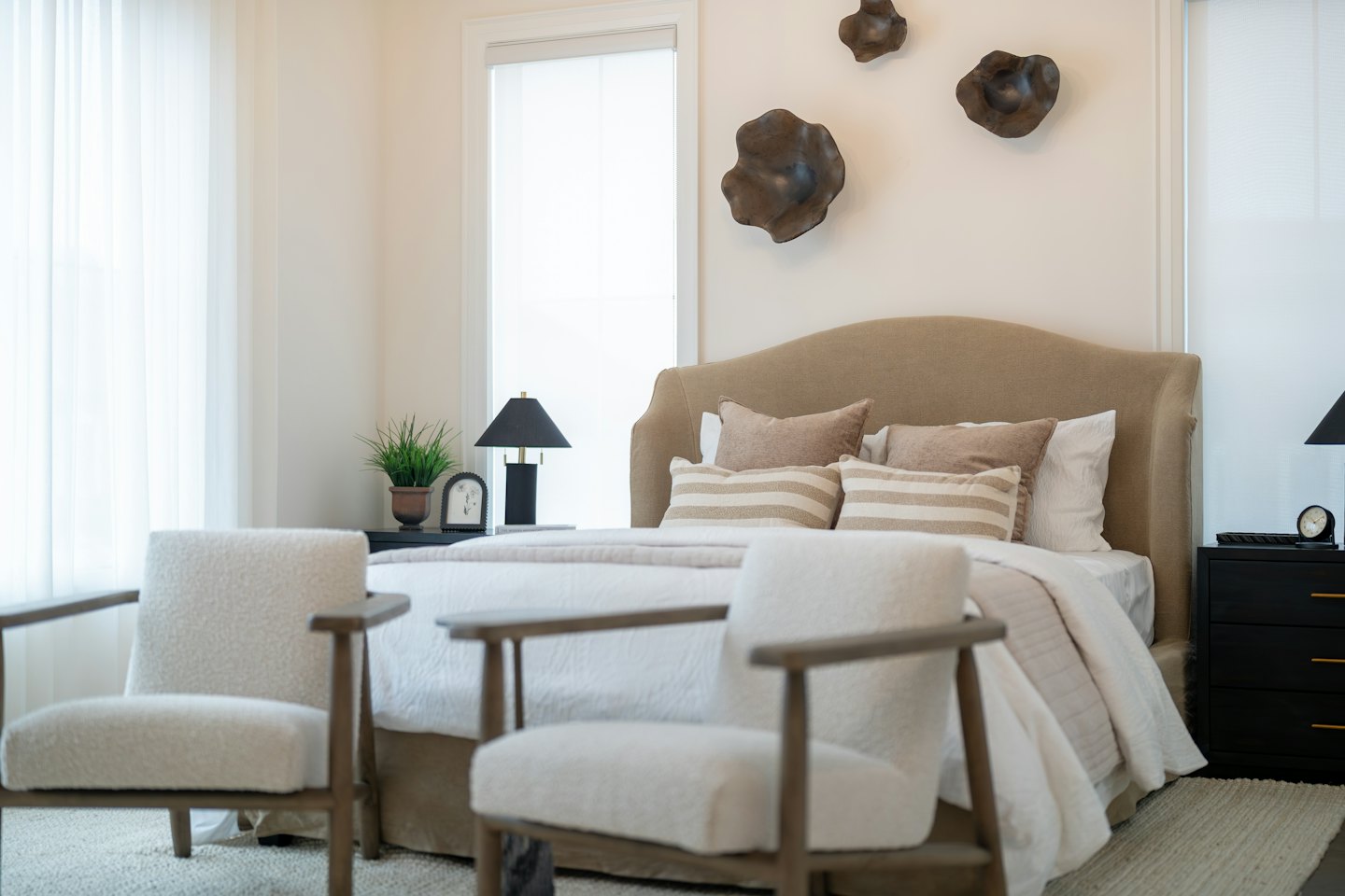 Modern bedroom with a bed and two armchairs.
