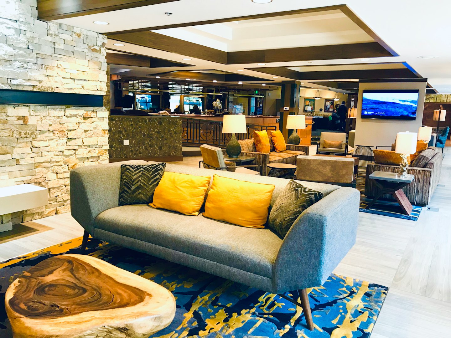 Modern hotel lobby featuring a sofa with colorful throw pillows.