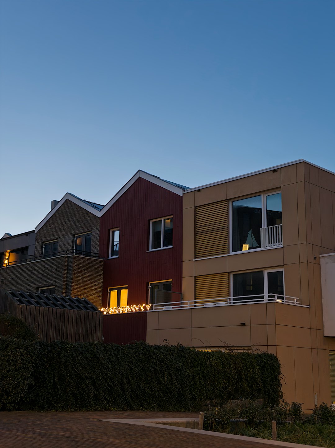 Modern residential buildings featuring glowing windows and string lights.